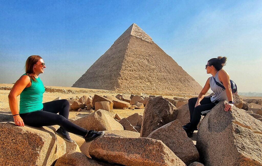 a photo showing 2 friends taking a seated photo in front of the great Pyramid