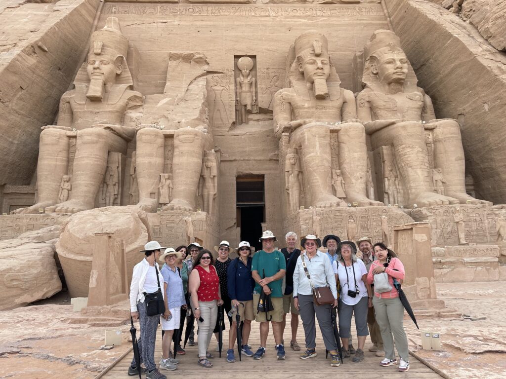 a photo showing tourists taking a pose in front of Abu Simbel in Aswan