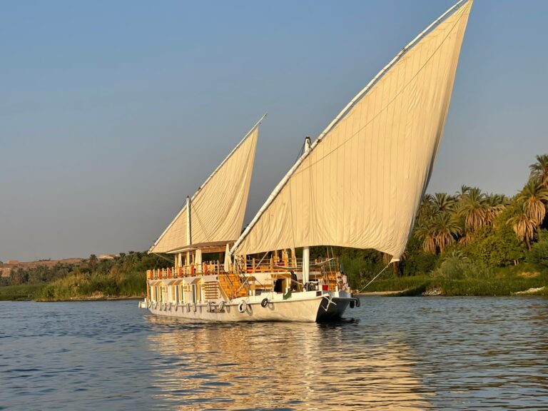 A photo of a dahabiya in the middle of the Nile in Egypt, sailing it's way through it.